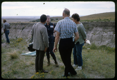 A photographic slide of a group of people gathered together outside next to some hills.