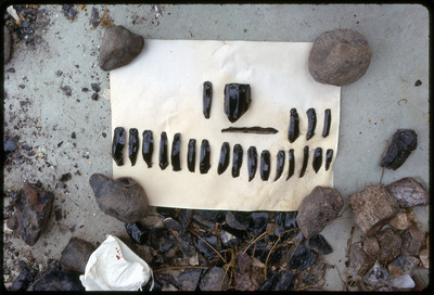 A photographic slide of a set of obsidian blades and the core they were struck from displayed on a leather pad.