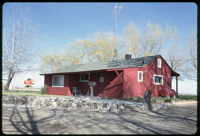 A photographic slide of a red house with a dirt driveway and a sign that reads "Bob Reese Motor Co".