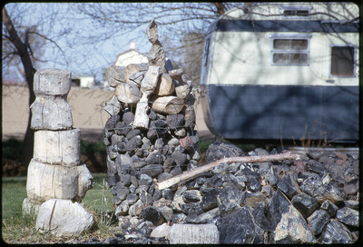 A photographic slide of a pile of obsidian rocks in front of an RV.