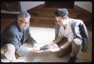 A photographic slide of two men holding an obsidian core.