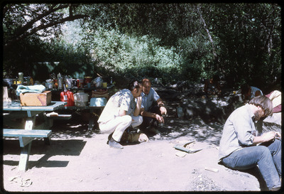 A photographic slide of a group of people flintknapping outside.