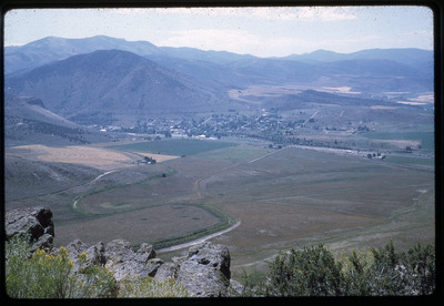 A photographic slide of a grainy view of a grassy field overlooking a small town.