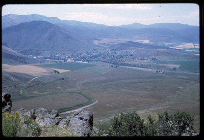A photographic slide of a grainy view of a grassy field overlooking a small town.