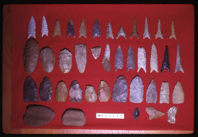 A photographic slide of a series of lithic points displayed on a red background.