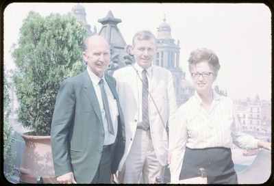 A photographic slide of Evelyn and Don E. Crabtree and another man standing in front of an ornate stone catheral.