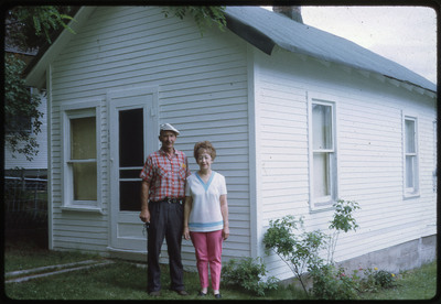 A photographic slide of Don E. Crabtree and a woman standing in the front of a white house.