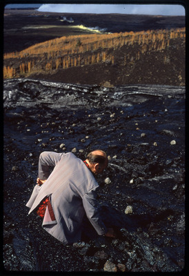 A photographic slide of Don E. Crabtree, fully dressed, wading in a river while searching for something at the bottom.