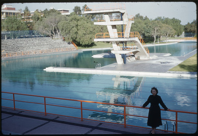 A photographic slide of Evelyn Crabtree standing in front of a swimming pool with an ascending set of diving boards.