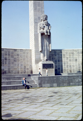 A photographic slide of a tall statue of a person in robes holding a child, with a description that reads "A La Que Nos Amo Antes De Conocernos". Don E. Crabtree sits in the foreground.