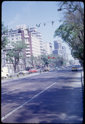A photographic slide of a road with paper decorations hanging overhead.