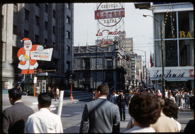 A photographic slide of a busy city square decorated with buildings, signs, and advertisements.