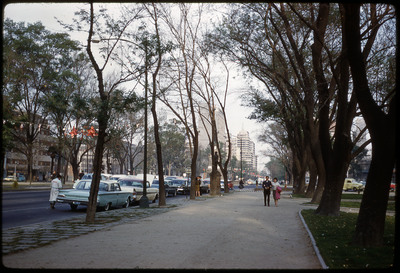 A photographic slide of a sidewalk along a busy city street.