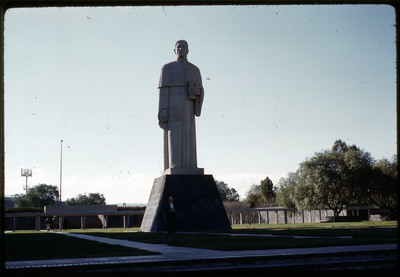 A photographic slide of a tall statue of a person holding a book.
