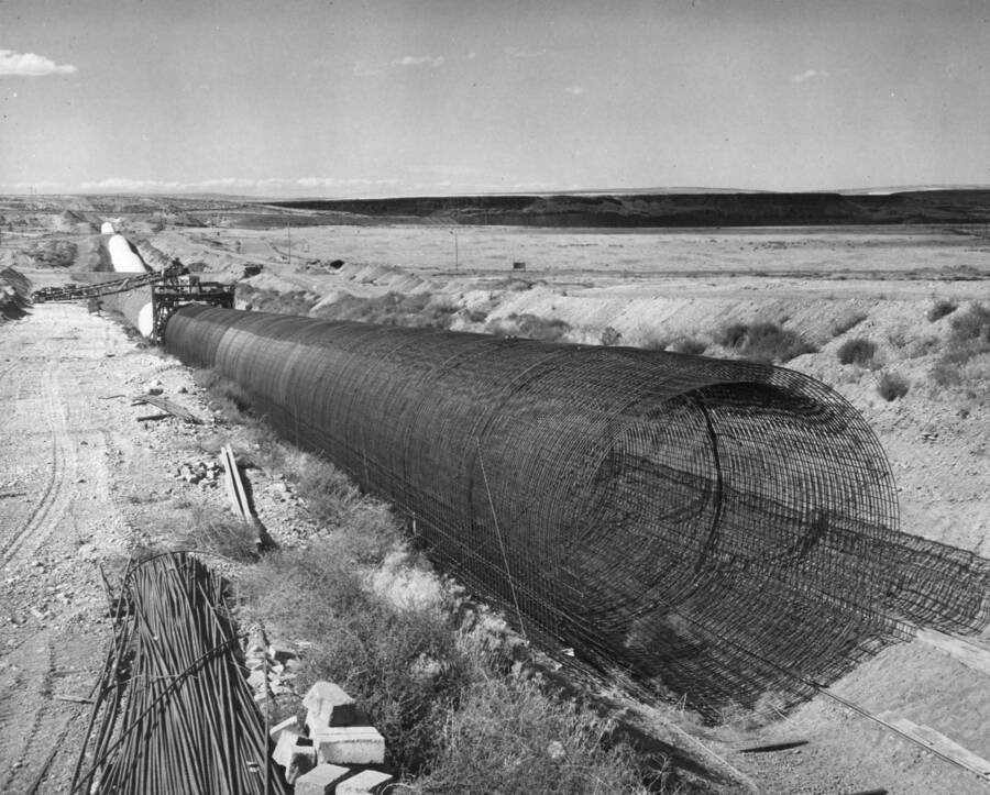Columbia Basin Project, Irrigation Division, East Low Canal, Specifications No. 1422--Utah Construction Co. and Winston Bros. Co., Contractor. Looking northeasterly over Crab Creek Siphon No. 1. Bifurcation works junction of Main, West, and East Low Canals is at the end of the siphon in left background. Fill over siphon beyond the form jumbo is crossing of P.S. Highway No. 7 Form stands at Section 95 and re-steel is in the place to Section 110 in foreground. Harold Foss, Photographer.