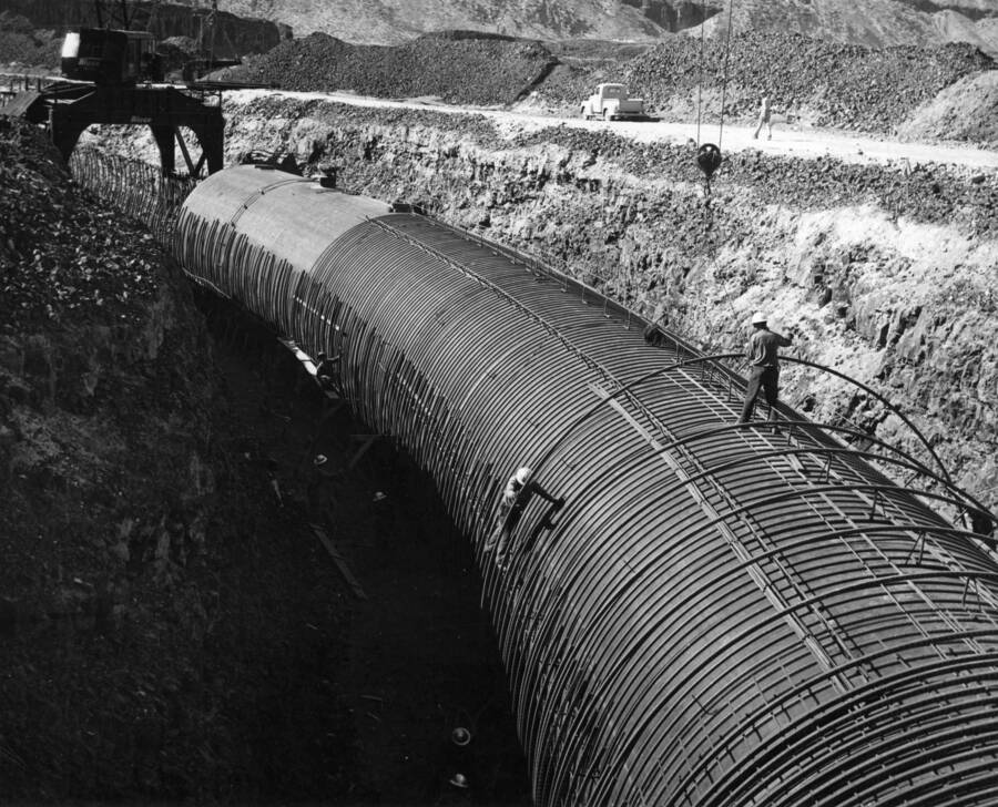 Columbia Basin Project, Irrigation Division, Soap Lake Siphon, Specifications No. 2411, Winston Brothers and Utah Construction Co., Contractors. This photograph is of the same area as photo No. 3220-04 but looking downstream. The men in the right foreground are placing the outer re-steel hoops. Curve P.I.= 468+54.95. H.E. Foss, photographer