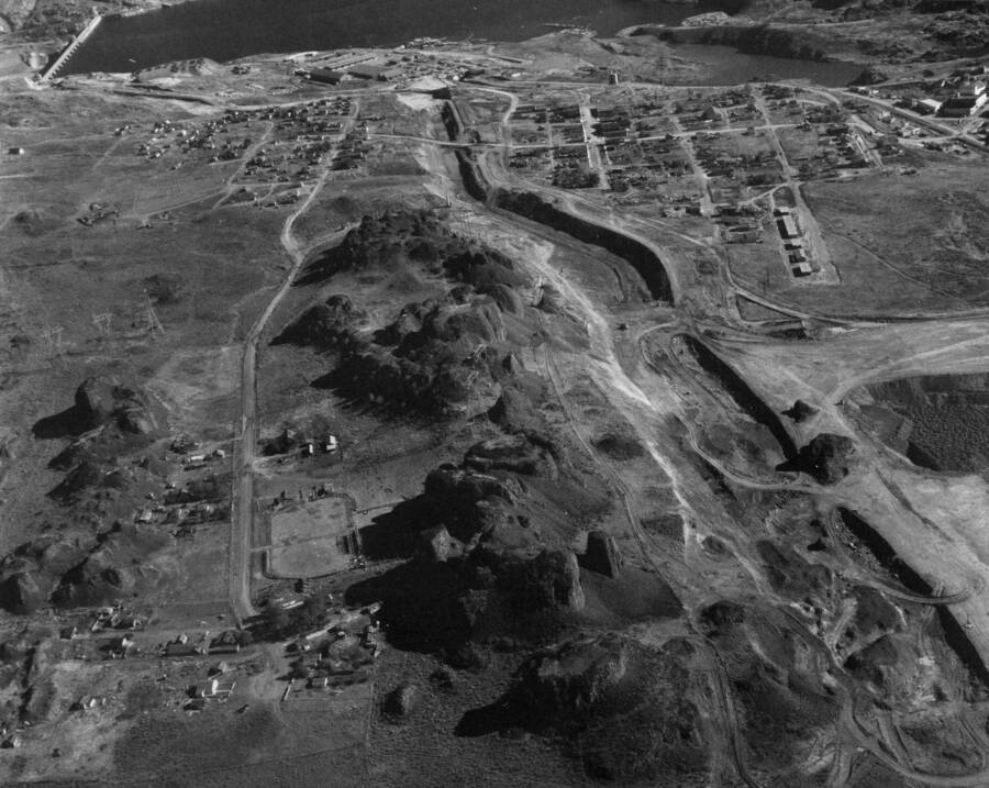 An aerial view looking east. A general view showing feeder canal, area immediately above slide area of canal, and part of town of Grand Coulee. Feeder canal shown back to headworks