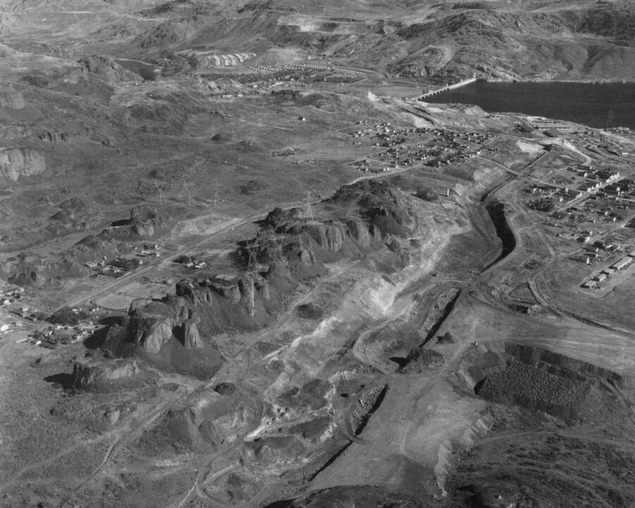 An aerial view looking northeast. A general view showing feeder canal, area above feeder canal, and part of town of Grand Coulee. Highest crack in slide area is visible. Feeder canal outline can be seen back to headworks. A view of the area above feeder canal from station 77 back to the headworks.