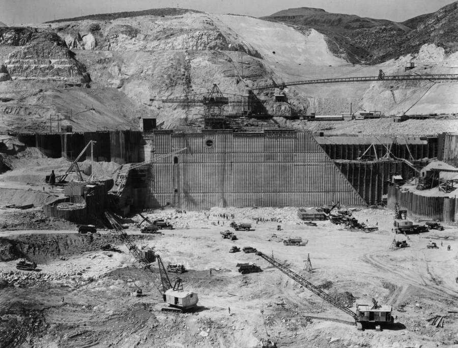 Columbia Basin Project, Grand Coulee Dam. Exposed bedrock in the center section looking west toward block 40. Derrick equipment mounted on the steel shell on the left and another which is to be mounted on the timber located on the rock, are to be used for cleanup of rock and placing concrete.
