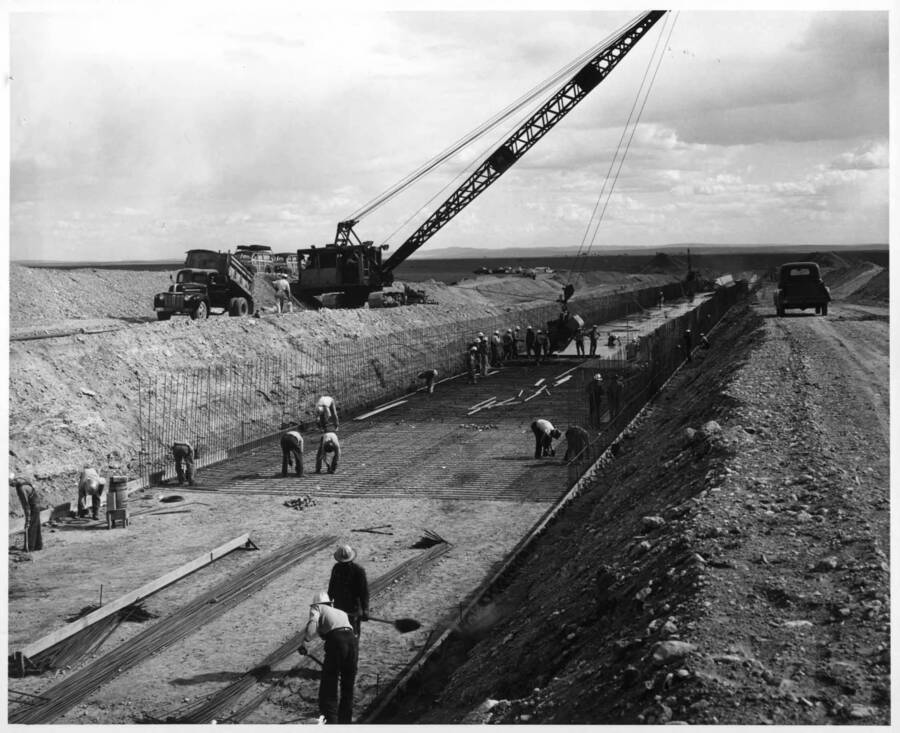 Columbia Basin Project, Irrigation Division, Winchester Wasteway, Specs. 2648. Placing concrete on the floor slap of the Winchester Wateway chute in the vicinity of station 21+00. In foreground workmen are placing the paving forms which serve as a base for the outside wall forms. Work is being performed by J.A. Tertling and Sons, Inc. under above Specifications. H.E. Foss, photographer