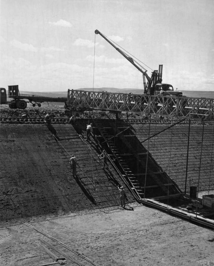 West Canal, Specs. 1286, Winston-Utah Co. Reinforcing steel crew at work, aided by truck-mounted crane on jumbo. Bridge of jumbo is a war-surplus Baily Bridge. Photo by F.B. Pomeroy.