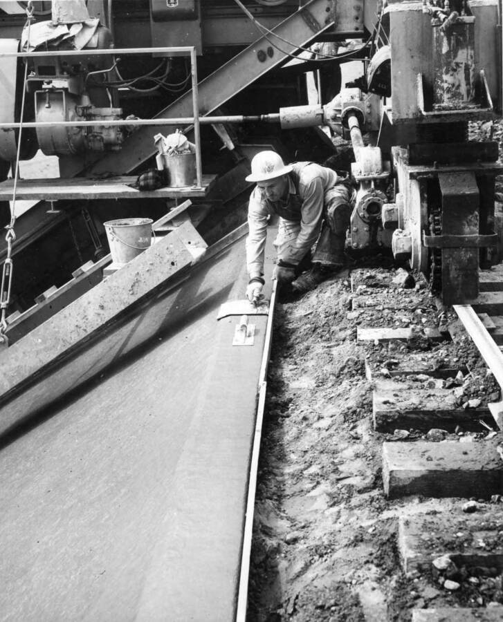 Columbia Basin Project, Irrigation Division, 2nd Section West Canal, Specs. 2541. Concrete finisher troweling the curb at the top edge of the lining with a specially shaped tool. Work is being performed by Morrison-Knudsen, Inc. under Schedule 2 of the above Specifications. H.E. Foss, photographer
