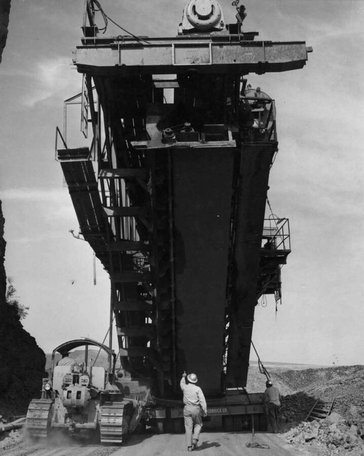 Columbia Basin Project, Irrigation Division, 2nd Section, West Canal, Specs. 2541. Moving the lining machine from the west to the east side of Soap Lake. The man walking behind the liner is pointing at the vibrating tube. Directly to the right, the vibrator is the slip form, then the press plate to which the longitudinal groove outers are attached. Work is being performed by Morrison-Knudsen, Inc. under Schedule 1 of above Specifications. H.E. Foss, photographer.