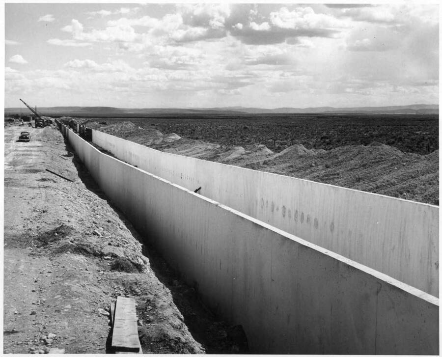 Columbia Basin Project, Irrigation Division, Specifications No. 2844, 3rd Section, West Canal, Schedule 3. Contractor: Minnis and Shilling. Looking downstream into chute from left bank at Station 1992+50 showing finished wall sections of chute. Concrete is being placed in forms set at station 2001+00 approximately. H. E. Foss, photographer