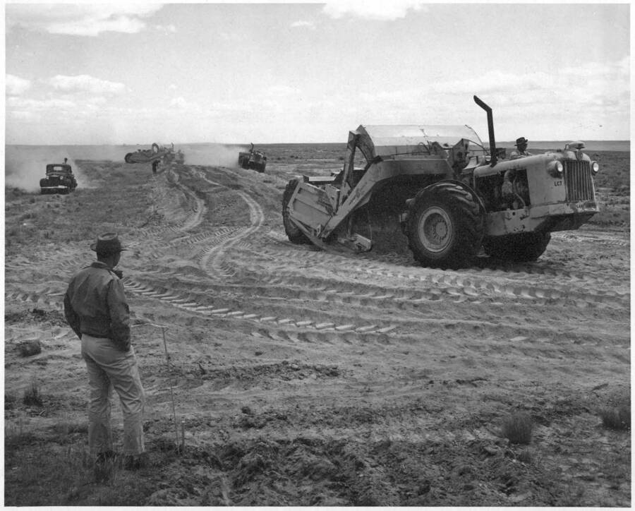 Columbia Basin Project, Irrigation Division, W-3 Laterals, Specs. 2880. Start of embankment construction on Lateral W-25 station 4+00 to 12+50. Borrow area is on right side of lateral within the R/W. Man in foreground is standing at left toe stake at station 4+00. Primary state highway #7 is in the background. Work is being performed by J.A. Tertling and Sons, Inc. Under Schedule 1 of above Specifications. H.E. Foss, photographer.