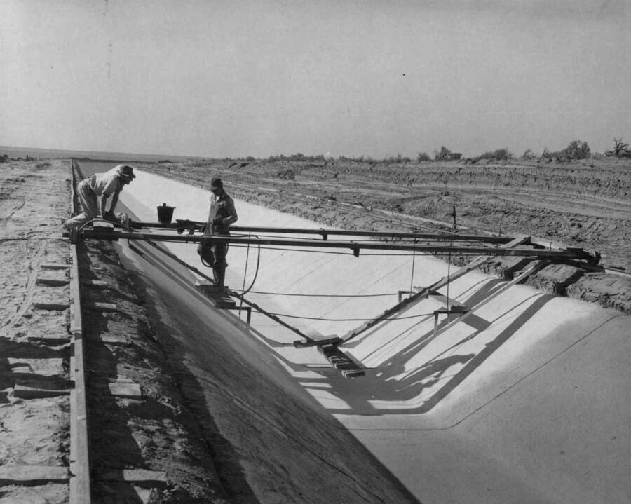 View showing application of curing compound to newly placed 3-inch concrete lining on the Pasco Pump Lateral system which is under construction by J. A. Terteling and Sons, Inc. Specifications 1230, PPL Sta. 45+00, 10 to 15 miles northwest of Pasco, Washington