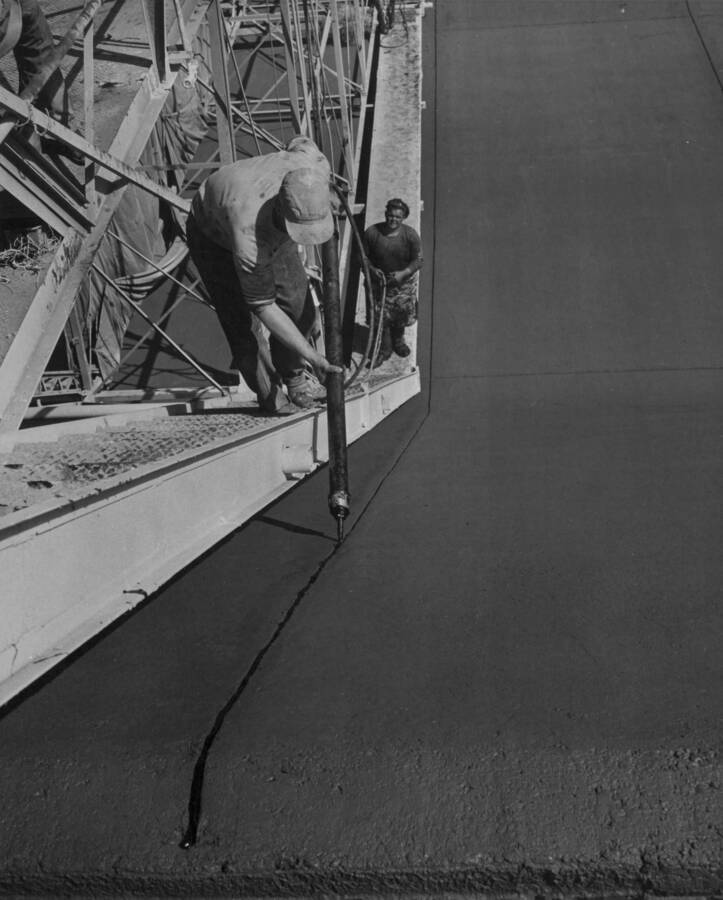 Columbia Basin Project--Irrigation division. Majestic joint filler being placed in transverse joint during lining operations on West Canal. Majestic joint filler and white pigmented curing compound application is handled from this jumbo which travels on the same track used by the lining machine. H.E. Foss, photographer