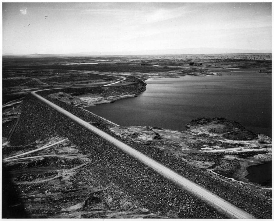 Columbia Basin Project, Irrigation Division, O'Sullivan Dam. Aerial view looking west, shows dam between stations 60+00 at extreme left and station 196+00 at lower right. The area seen above the dam will be largely covered when the water behind the dam is operation level. H.E. Foss, photographer.