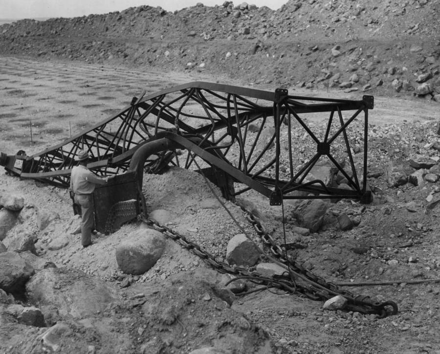 Columbia Basin Project, Irrigation Division, East Low Canal. Spec. #1422--Utah Construction Co. and Winston Bros. Co. Contractor. View showing section of 125 feet dragline boom from contractors Marion 151-M 6cu.yd. dragline after it collapsed at Station 380+00. Exposed rock after completion of drilling operations in center background. A.W. Bauman, Photographer