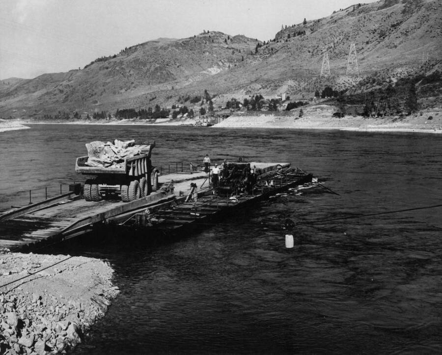 Photograph of the cross-river ferry taken from the left side ramp. Detail of the 4-drum hoist and the cables required to maneuver the ferry may be noted. This ferry is being used to carry some 350,000 tons of riprap and armor rock from the Bull Canyon quarry to the right riverbank for slope protection. Grand Coulee Dam, River Channel Improvements, Specifications 2808, Contract Ir-18762, Morrison-Knudsen Company, Inc., Contractor.