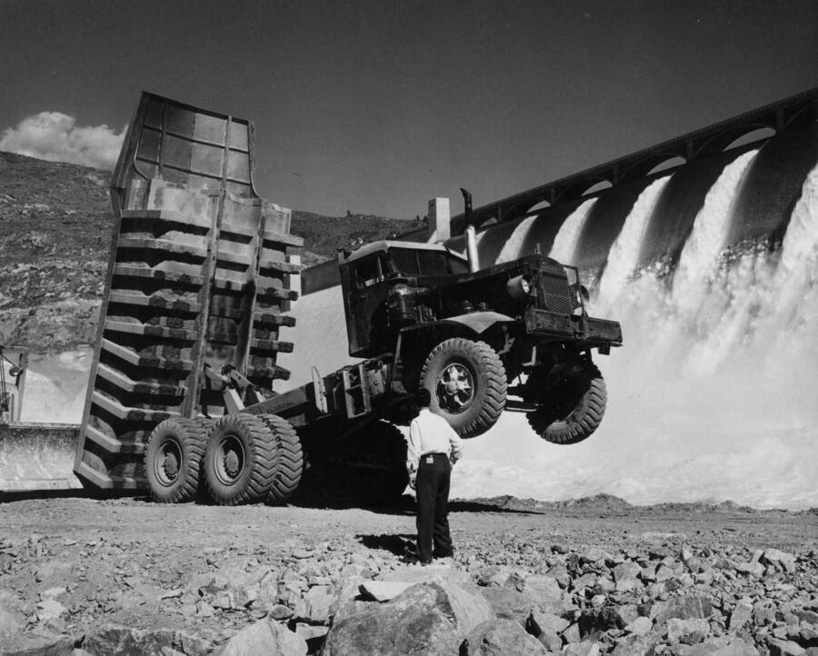 Although this truck alone weighs almost 60,000 pounds, it's not uncommon for one or two huge granite armor rocks to lift the front wheels clear of the ground. A dozer, blade visible at left, solved the truck drivers dilemma in this problem. The trucks can carry 20-30 tons, and sometimes one rock is an entire load. Approximately a year and one-half will be required to line the banks for close to one mile downstream from the Grand Coulee Dam.