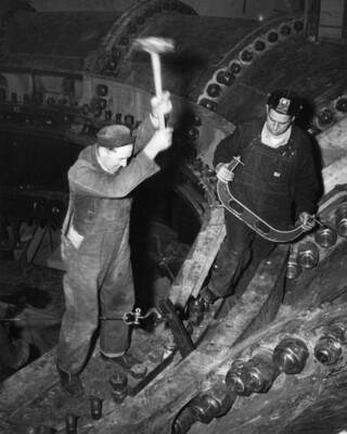 Bureau workmen Stretching bolts on scroll case in east powerhouse at Grand Coulee Dam, Left to right; Walt Scott and Robert Bush