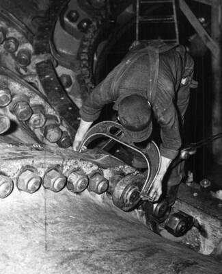 Workman using a micrometer on L-6 scroll case bolts after tightening.