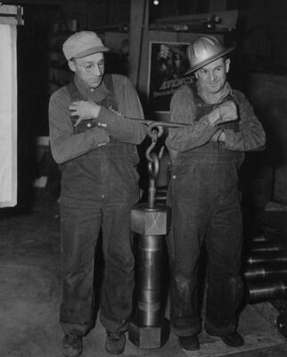 Bolts and nuts weighing 193 pounds, couple the sections of the shafts for the two 75,000 kilowatt Shasta generators being installed in the Grand Coulee Dam left powerhouse. The bolts are five inches in diameter and 25 inches long. Each section of the two part shaft is provided with a flange, in which 16 holes have been bored. The bolts will be inserted in these openings, and the nuts, weighing 37 pounds each, attached. To tighten these, a huge steel wrench, three feet long, turned by the blows from a heavy sledge hammer, will be used. Before being seated, the bolts will be cooled to 80 below zero, and shrunk, in a compartment filled with dry ice. While in their contracted form, they will be inserted in the openings in the flanges of the shaft. When their temperature again rises and matches that of the surrounding atmosphere, the fit will be as near perfect as engineers are able to make it.