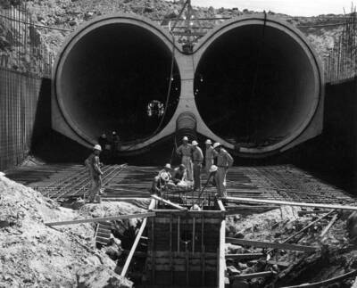 Feeder Canal. This photograph was taken at about station 75+15 in the invert of the outlet open transition of the cut-and-cover looking east at the downstream end of the barrel section. The contractor is erecting forms, and placing reinforcing steel for the contractor is erecting forms, and placing and tying reinforcing steel for the underdrain pump well at the downstream end of the round-to-square transition. Specifications No. 2586, J.A. Terteling and Sons, Inc., Contractor.