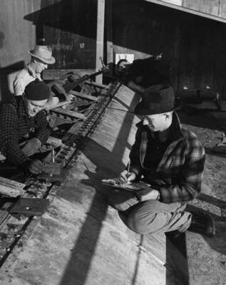 Men align drum gate hinges