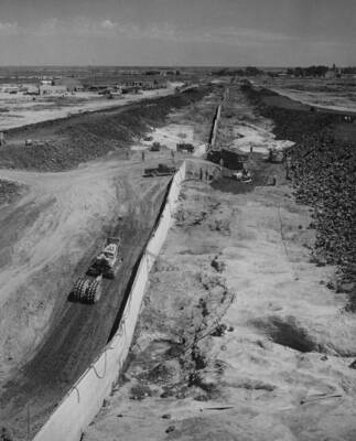 South Coulee Dam--Cleanup placing operations on foundation, station 71+50 to 74+00. Narrow-drum roller is compacting Zone 1 and Zone 2 embankment upstream of cutoff wall. The dozer is preparing a ramp to facilitate cleanup work in inaccessible potholes downstream from centerline.