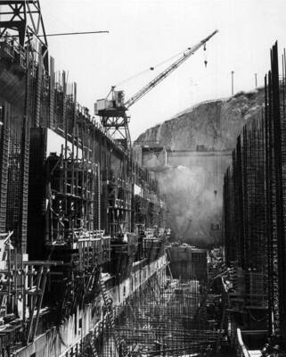 Feeder Canal. Specs. 2586. J.A. Terteling and Sons Inc., Contractors. This photograph was taken on the extreme west end of the Electric City Storage Yard. The sub-contractor, the Steel Construction Co., who have the contract with J.A. Terteling and Sons for furnishing and installing reinforcing steel is fabricating concrete support blocks for the reinforcing steel. In the left center of this photo are forms for 6' blocks and right center are forms for 2 3/4' blocks. The contractor will fill these forms with a mix of 2 1/2 of sand to 1 cement, then, after this has partially set, the blocks are cut up into desired sizes.