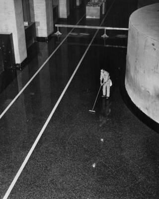 Terrazzo machine man applying linseed oil and turpentine to floor and base of Unit L-1, elevation 991, West Powerhouse. This oil is floated for at least six hours before being removed.