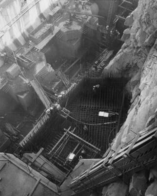 Construction of the Pumping Plant Structure, Grand Coulee Dam, Coulee Dam, Washington. Installation of pumping unit P-2 discharge pipe, showing reinforcing steel being placed in concrete form is the square opening of the block out which extends under the steel matt into the tunnel. Foreground, on top of the steel matt, steel is being placed to form block out for the elevator, also a ladder is shown on the west wall. In the background, at the bottom of the downstream wall are the intake pipes for pumping units P-2, P-3 and P-4