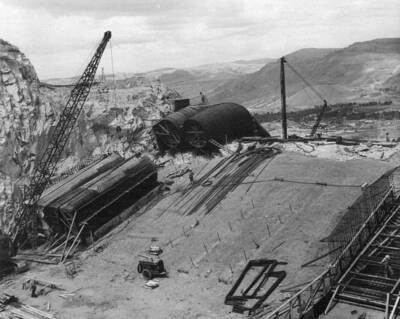 Specifications 2329, Morrison-Knudsen So., Inc. and Peter Kiewit Sons' Company. Progress view showing initial construction on the pump discharge outlet structure. On the right can be seen the completed invert of P-1 and P-2 conduits with the sectional forms of the transition arch being set. On the left is the P-9 transition invert form being made ready to pour. The crest bend sections of P-1 and P-2 discharge pipes have been secured into final position, braced to retain round, and the inner girdle of reinforcing steel is being placed.