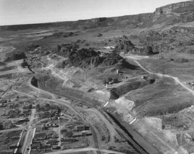 An aerial view of the feeder canal looking west. The surface runoff chutes on the right slope of the canal in the foreground area are at stations 45+05 and 48+60, respectively. The slide cracks are visible at the left center. A good view of the right side of upper end of the Grand Coulee and area above feeder canal slide area.