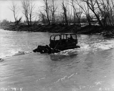 Bulldozer operating midstream on the Grande Ronde River upstream from La Grande, Oregon, in restoration effort of re-establishing river channel and shoring up the eroded embankments caused by the late January flood.