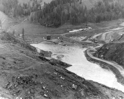 Fifty-foot high, four decked jumbo drill rig that will be used to bore the diversion tunnel at the U.S. Army Corps of Engineers' Dworshak Dam on the North For Clearwater River. Thirty air-driven "Swedish ladder drills" will be distributed along the face of the mobile drill rig and will be advanced forward yard by yard as the tunnel bore is pushed ahead. The schedule calls for the thirty borings across the face of the tunnel to be loaded with explosives, the drill frame pulled back out of the tunnel, and the charge exploded at each change of shift. The bore will be 1,573 feet in length, with a vertical height of approximately 50 feet and a horizontal width of 40 feet.