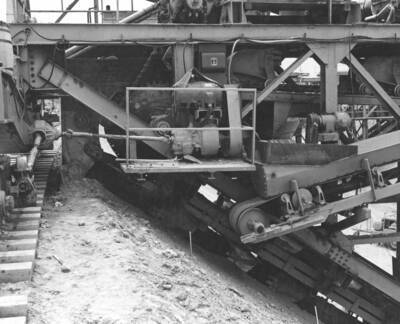 Columbia Basin Project, Irrigation Division, 2nd Section West Canal, Specs. 2541. Close-up showing drive mechanism excavating buckets and conveyor belts on the right front side of the trimmer. Left side is similar. Work is being performed by Morrison-Knudsen, Inc. under Schedule 2 of above Specifications. H.E. Foss, photographer.