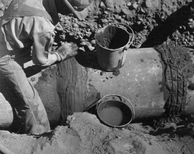 Laying 21 inch reinforced concrete pipe (Class A-50' head) on the burbank pump laterals EP 1.1 station 50+50. note placing of wire mesh reinforcement for band. This feature under construction by Mathews Brothers about 7 miles east of Pasco, Washington. Specifications R1-CB-13